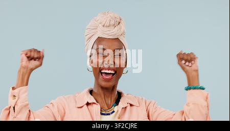 Donna felice, vincente e nera con pugno alzato per il successo aziendale su uno sfondo da studio. Persona femminile eccitata o sorriso con successo o bene Foto Stock