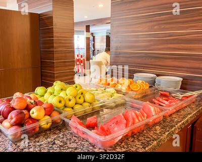 Buffet di frutta fresca in un ristorante di hotel con anguria, mele, arance e melone serviti su un bancone self-service durante la colazione all-inclusive, l Foto Stock