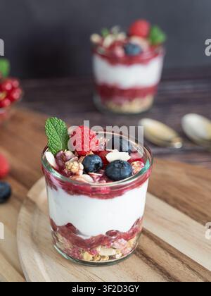 Fotografia ravvicinata di cibo di un dessert allo yogurt a strati con frutti di bosco, granola e guarnizione di menta fresca Foto Stock