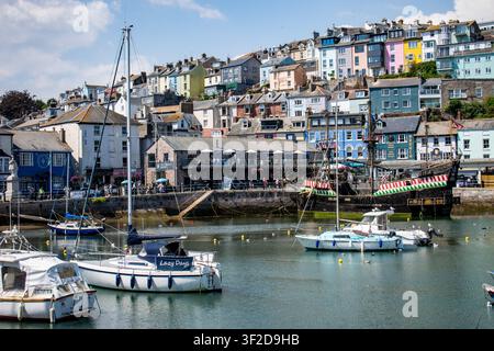 Il porto di Brixham nel Devon con yacht, la replica del Golden Hind e case colorate sul pendio di una collina in una giornata estiva soleggiata. Foto Stock