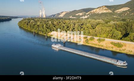 Saulce-sur-Rhone, Francia – 12 luglio 2026: Vista aerea di una chiatta di carico sul Rodano con la centrale nucleare di Cruas e le torri di raffreddamento in Foto Stock