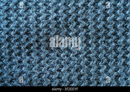 Un primo piano, vista dall'alto, mostra un tessuto a maglia blu scuro e strutturato. Il motivo è un punto zigzag costante con fibre visibili che creano una superficie ruvida Foto Stock