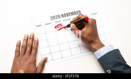 Uomo africano che scrive il testo del voto in Calendario, elezioni generali degli Stati Uniti Foto Stock