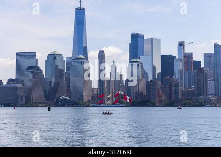 Jersey City, Stati Uniti - 04 luglio 2026: Vista del Liberty State Park con lo skyline di Manhattan e una nave a vela sull'Hudson River sotto un cielo sereno Foto Stock