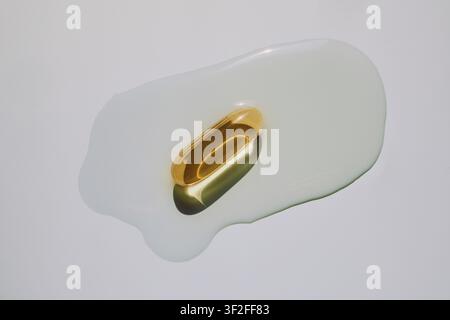 Capsula di olio di fegato di merluzzo dorato immersa in liquido oleoso trasparente Foto Stock