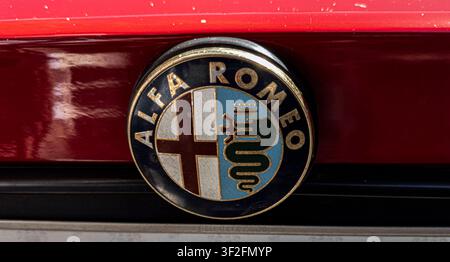 TAVERNES BLANQUES, SPAGNA - 14 GIUGNO 2026. L'emblematico stemma di Alfa Romeo si trova in modo prominente sul cofano di un'auto rossa classica. Questo badge vintage mostra Foto Stock