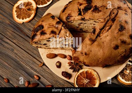 Torta di Genova Pandolce Genovese tradizionale decorata con rami di abete freschi e tela di sacco rustica, circondata da fette di arancia essiccate, bastoncini di cannella e noci Foto Stock