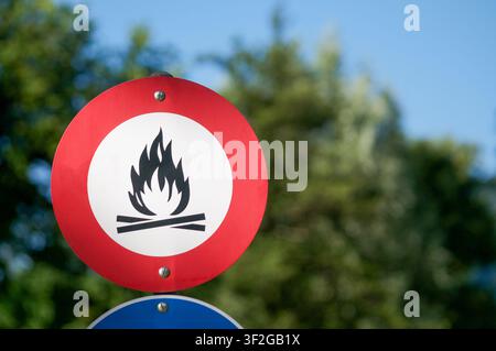Vista ravvicinata di un cartello di divieto rotondo che vieta falò e fiamme libere, montato su un palo all'aperto. Segnale di avvertimento di sicurezza Foto Stock