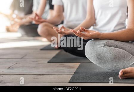 Gruppo di persone irriconoscibili meditando in posizione Lotus e mostrando Gesti Mudra Foto Stock