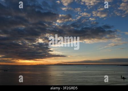 Una vasta veduta aerea sulla costa di Xiamen cattura un maestoso cielo di alba tempestosa, con masse di nuvole scure che si separano per rivelare una luce vivida arancione e ambra Foto Stock