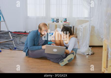 Coppia sposata acquista online attrezzi per la ristrutturazione durante un rinnovamento dell'appartamento, pianificando riparazioni, forniture decorative e lavori di miglioramento della casa. Foto Stock