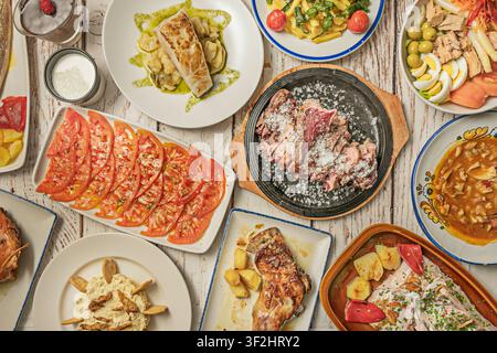 Tavolo di tapas spagnole: Carne croccante al sale, insalata di pomodori affettati, pesce grigliato, pesce arrostito con peperoni e salpicón Foto Stock
