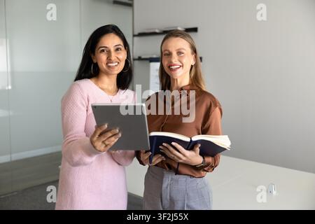 Colleghe donne multietniche sorridenti, che posano per un ritratto professionale in ufficio Foto Stock