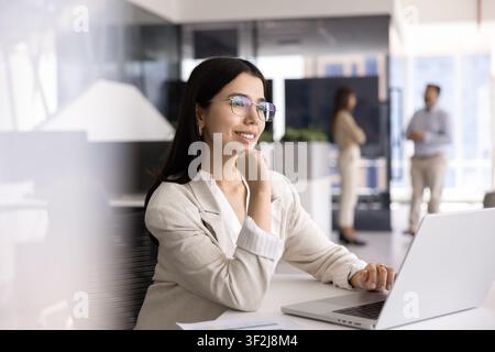 Giovane donna professionista che lavora su un laptop in un ufficio moderno Foto Stock