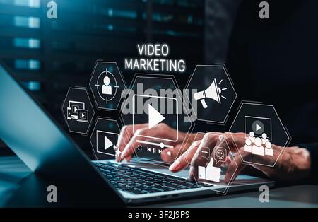 Concetto di strategia di marketing video. Marketer che utilizza un laptop con icona di coinvolgimento mediatico, pubblicità online, targeting del pubblico, promozione, interazione sociale Foto Stock