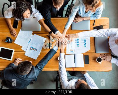 Business People tenere insieme le mani durante la riunione seduta in ufficio Foto Stock