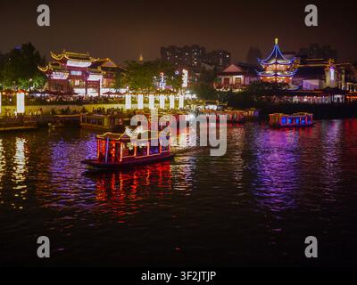 Barche turistiche illuminate che navigano sul fiume Qinhuai vicino al Tempio di Confucio di notte a Nanjing, Jiangsu, Cina Foto Stock