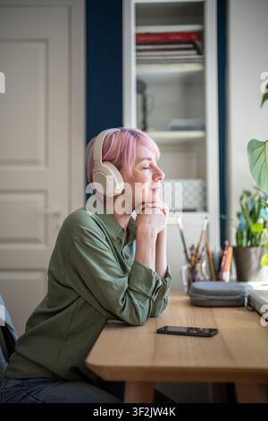 Donna positiva soddisfatta che ascolta una playlist musicale online su un'app di streaming per smartphone con le cuffie. Foto Stock