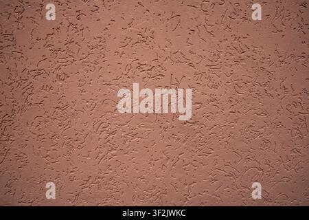 Parete in intonaco di terracotta decorativa con superficie ruvida e testurizzata astratta e motivo irregolare Foto Stock