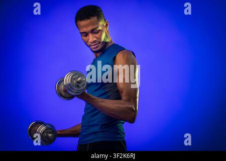 Determinato uomo che esercita con i rumbbells su sfondo blu Foto Stock