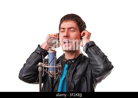 Un giovane canta in un microfono da studio professionale su uno sfondo bianco. Foto Stock