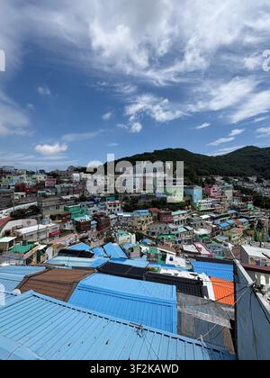 Vista aerea del villaggio culturale di Gamcheon, Busan, Corea del Sud, con case colorate addossate l'una all'altra che scendono a cascata lungo un pendio sotto un cielo nuvoloso drammatico. Foto Stock
