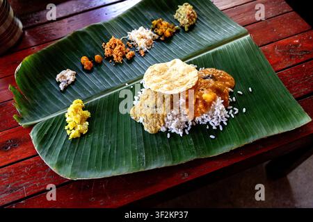 Banche indiane del sud servite su una foglia di banano con riso e una varietà di curry, Isola di Munroe, Kerala, India. Foto Stock