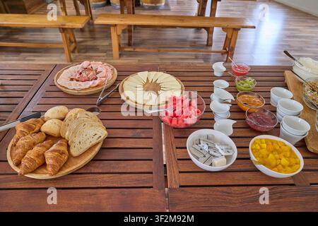 Colazione continentale con pasticcini, frutta e formaggio su tavolo di legno. Foto Stock