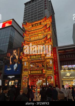 13 novembre 2025, Chengdu, Sichuan, Cina – Facciata di pagoda dorata a più livelli ornata di un negozio di gioielli di lusso in una vivace zona pedonale del distretto di Jinjiang. Foto Stock