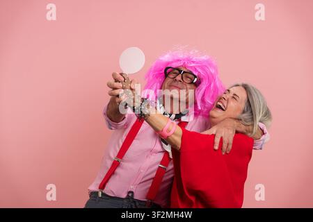 Allegra coppia matura che si diverte tenendo uno specchio Foto Stock