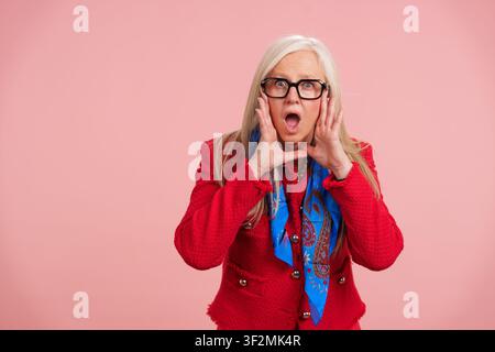 Anziana che grida notizie entusiasmanti con le mani a forma di bocca Foto Stock