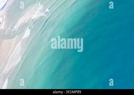 Ripresa aerea con droni che guarda direttamente una costa incontaminata con acqua azzurra limpida e riva deserta Foto Stock
