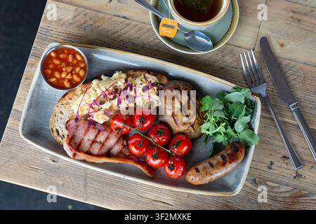 Deliziosa colazione con uova, salsiccia e pancetta affumicata su pane croccante Foto Stock