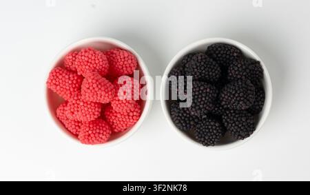 Bacche gommose in ciotola isolate, lamponi gommosi, more gelatine, caramelle di gelatina rossa e marmellata di frutta nera ricoperta di piccolo zucchero croccante Foto Stock