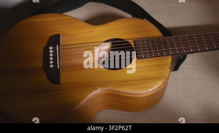 Chitarra acustica appoggiata su un tessuto morbido alla luce calda Foto Stock