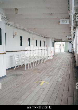 Filiera di sedie a sdraio in legno bianco lungo il ponte passeggiata coperto del transatlantico Hikawa Maru Foto Stock