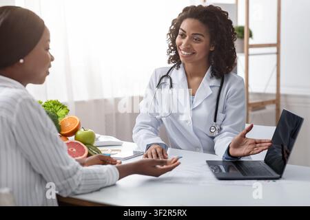 Sorridente medico nutrizionista avendo conversazione con il suo paziente Foto Stock