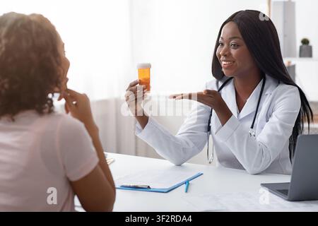 Medico afro femminile che prescrive la medicina al paziente Foto Stock