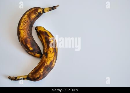 Due banane troppo mature su sfondo bianco Foto Stock