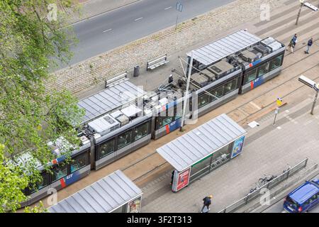 Rotterdam, Paesi Bassi – 16 maggio 2026 – Vista aerea ad angolo alto di un moderno tram elettrico RET parcheggiato su una piattaforma di una fermata in una strada cittadina con pa Foto Stock