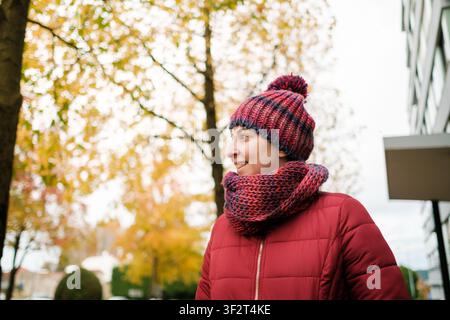 Donna felice che gode del tempo autunnale indossando un cappello di lana colorato e una sciarpa Foto Stock
