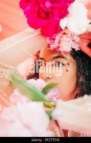 Donna con trucco a farfalla che sbircia tra fiori rosa Foto Stock