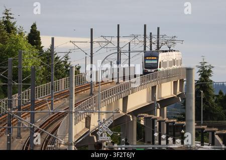 Redmond, Washington, USA – 28 giugno 2026: Tramvia leggera su un binario sopraelevato che si avvicina alla stazione di Overlake Village sotto un cielo nuvoloso. Foto Stock