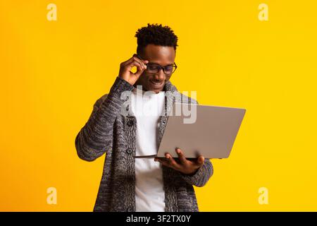 Programmatore uomo africano americano con portatile su giallo Foto Stock