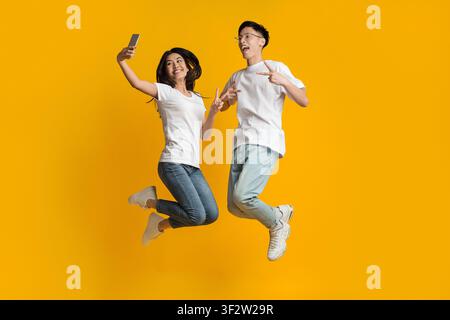 Pazzi coppia asiatica saltare e prendere selfie sullo smartphone Foto Stock