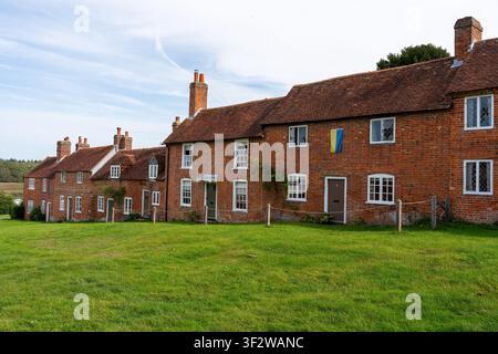 Vista dei cottage storici in mattoni rossi di Bucklers Hard, con architettura tradizionale e un prato verde in primo piano, Bucklers Hard, Inghilterra Foto Stock
