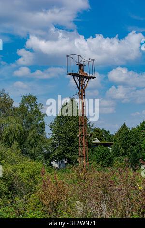 Vecchia piattaforma industriale in ferro arrugginita circondata da alberi verdi sotto un cielo blu nuvoloso a Coesfeld, Germania Foto Stock