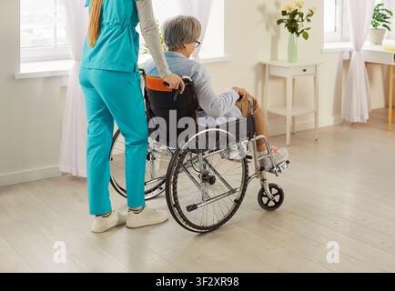 Medico O Infermiere Che Spinge Un Paziente Anziano In Sedia A Rotelle All'ospedale Foto Stock