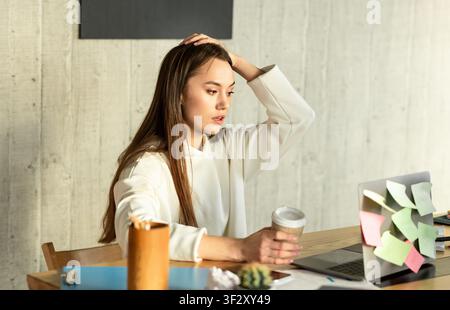 Donna freelance in shock e tenendo la testa Foto Stock