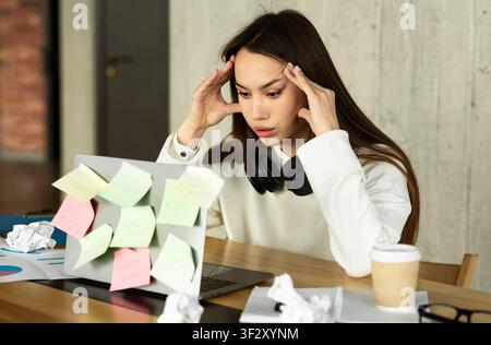 Difficoltà di lavoro. Donna che tiene la testa davanti al notebook Foto Stock